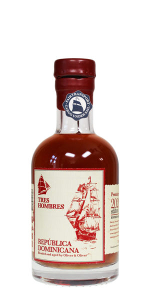 Tres Hombres Rum in einer kleinen, aus durchsichtigem Glas gefertigten 0,2l Flasche. Auf dem Flaschen-Etikett ist ein Segelschiff abgebildet, das den Fairtransport des Rums aus der Dominikanischer Republik symbolisiert.